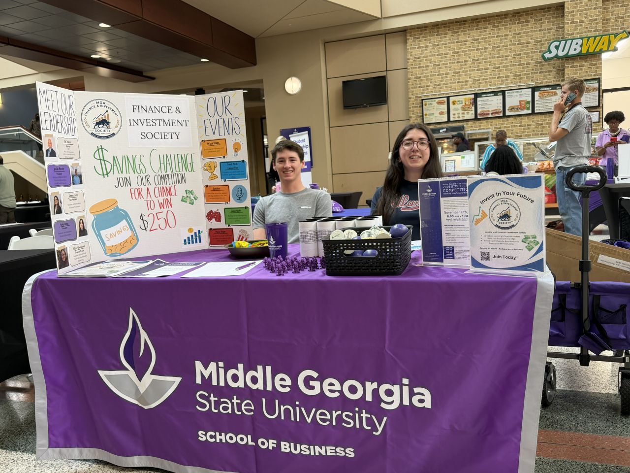 Two finance and investment society members at a display table recruiting new members